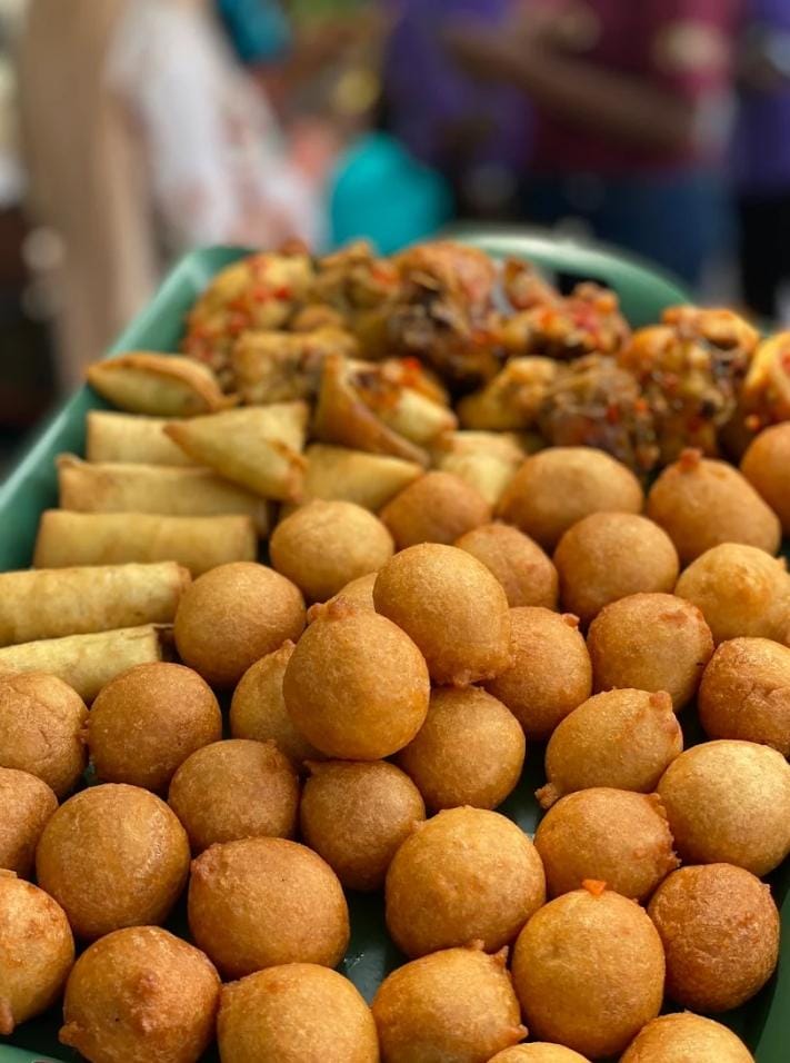 Close up of puff puff, spring rolls and grilled chicken